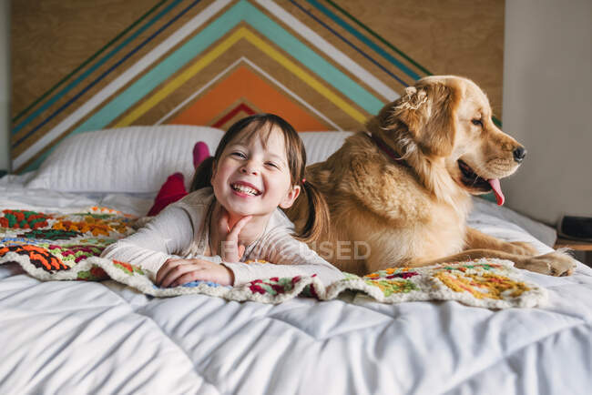 Молодая девушка играет с собакой на кровати — стоковое фото