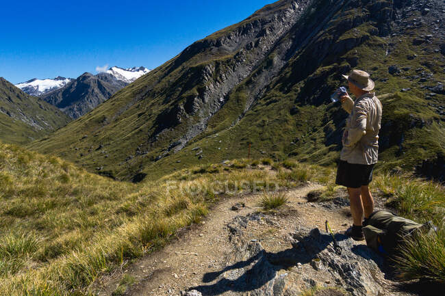 Hiker take a water break, Rees Saddle, Rees-Dart Track, Mt Aspiring National Park, South Island, New Zealand — стокове фото