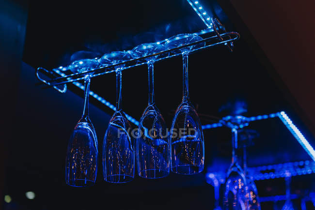 Vista de baixo ângulo de taças de champanhe penduradas em um cabide de vidro em um bar — Fotografia de Stock