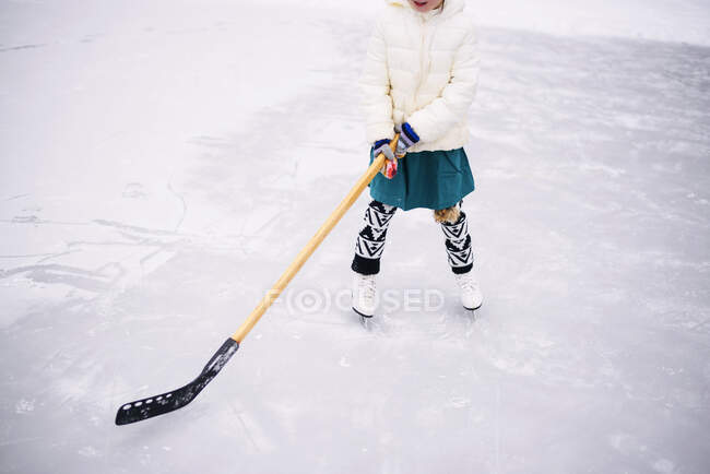 Ragazza che gioca a hockey su ghiaccio sul lago congelato — Foto stock