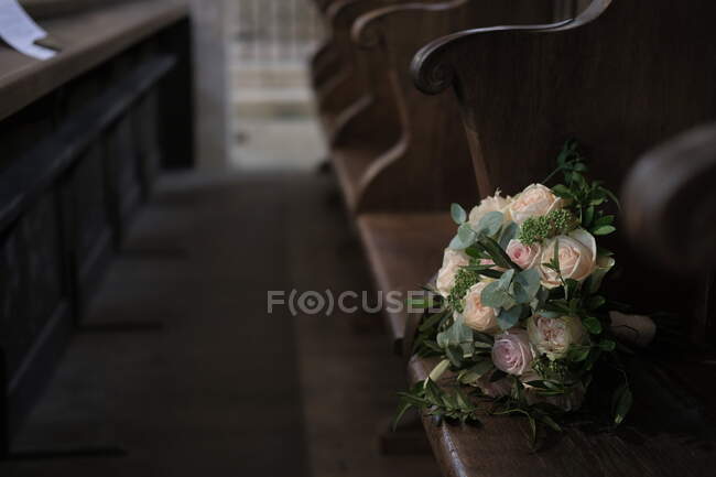 Bouquet of roses on a bench in a church — Stock Photo