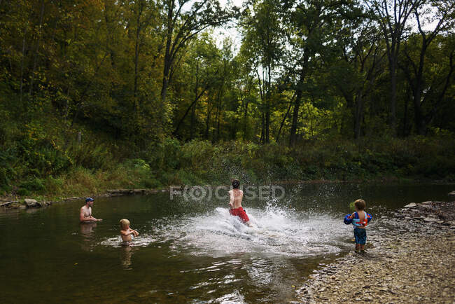 Homem correndo em um rio com seu amigo e dois meninos — Fotografia de Stock