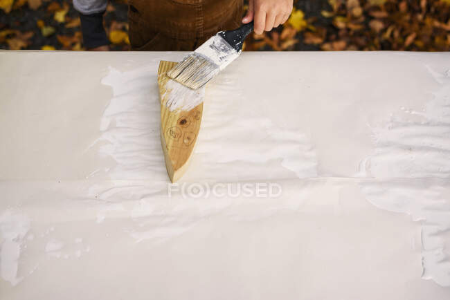 Garçon peignant une décoration fantôme en bois pour Halloween — Photo de stock