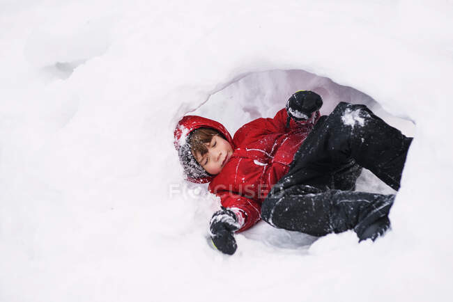 Junge liegt im Freien in einem Schneeloch — Stockfoto