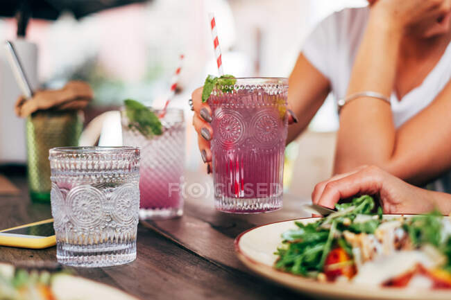 Two women sitting at a table eating and drinking — Stock Photo