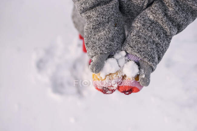 Vista aérea de las manos de una niña sosteniendo la nieve - foto de stock
