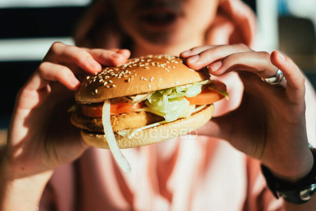 Tiro recortado de la mujer sosteniendo hamburguesa - foto de stock