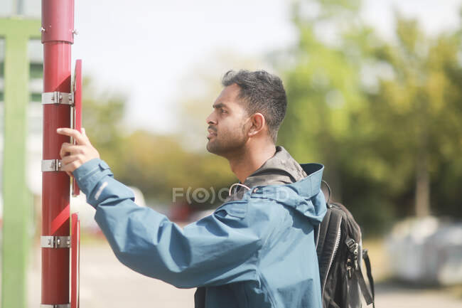Uomo in piedi ad una fermata dell'autobus guardando l'orario, Germania — Foto stock
