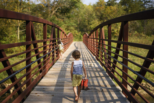 Tres niños caminando por un puente - foto de stock