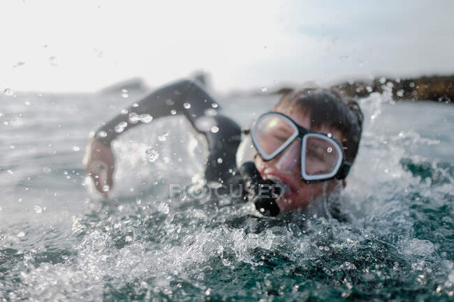 Boy swimming in ocean wearing a snorkel and mask, Orange County, United States - foto de stock