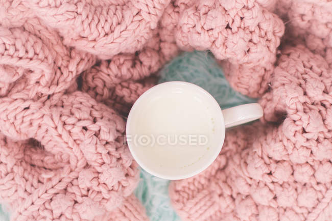 Tasse avec du lait chaud et une couverture tricotée — Photo de stock