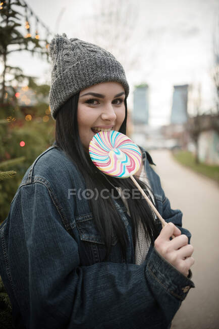 Retrato de una mujer sonriente comiendo una piruleta - foto de stock