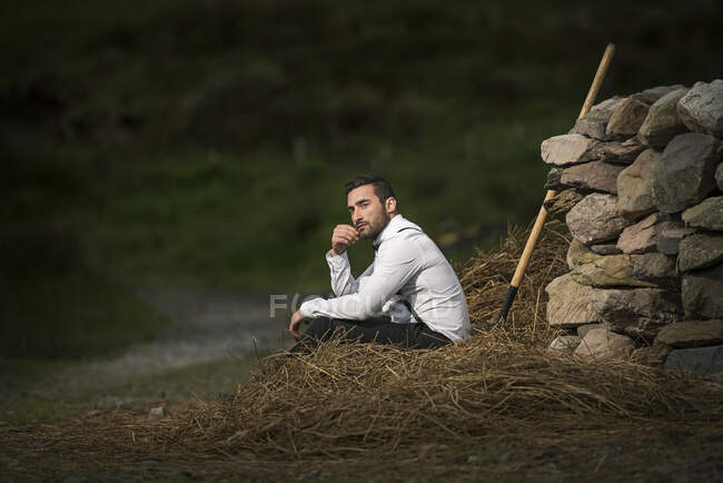 Landwirt sitzt auf einem Heuhaufen, Irland — Stockfoto