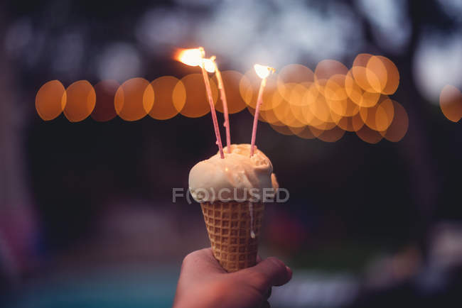 Mulher mão segurando um cone de sorvete com velas — Fotografia de Stock