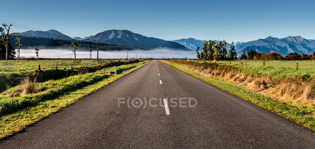 Estrada reta em direção às montanhas, South Island, Nova Zelândia — Fotografia de Stock