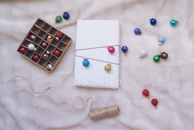 Рождественский фон с украшениями и подарочной коробкой на белом — стоковое фото