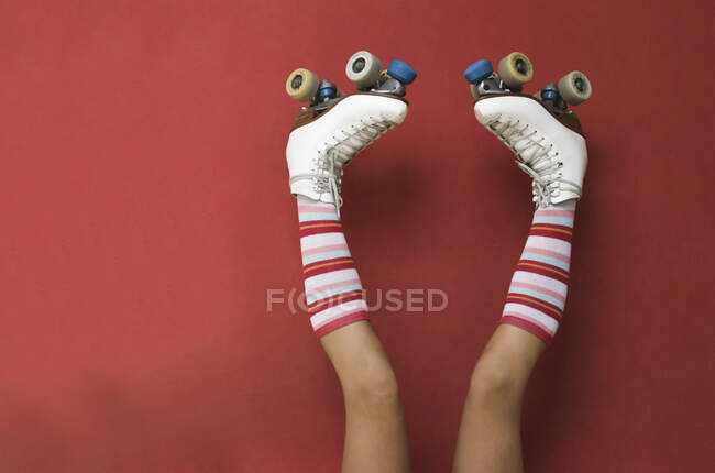 Patas de niña con calcetines largos y patines al revés contra una pared - foto de stock