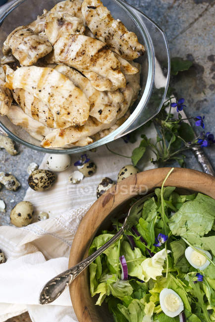 Pollo a la parrilla y ensalada con huevo de codorniz y flores comestibles - foto de stock