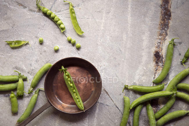 Vista aérea de uma frigideira de cobre e ervilhas frescas — Fotografia de Stock