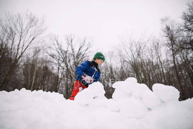 Garçon construire un fort de neige dans le jardin sur la nature — Photo de stock