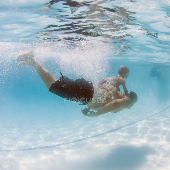 Niño nadando bajo el agua con su hermano, Condado de Orange, California, Estados Unidos - foto de stock