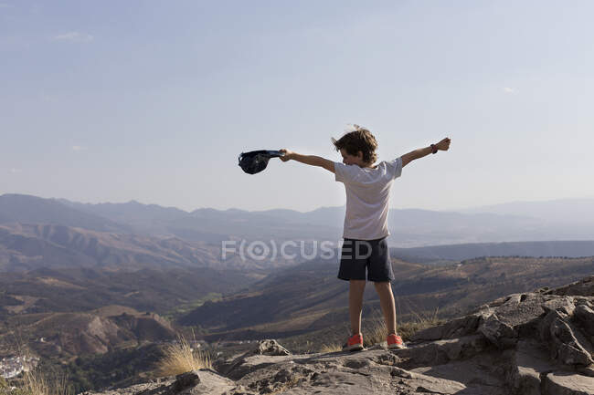 Хлопчик стоїть на горі з простягнутими руками — стокове фото