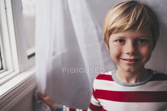 Ritratto di un ragazzo con lentiggini accanto ad una finestra — Foto stock