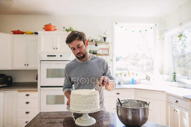 Человек, стоящий на кухне и украшающий торт — стоковое фото