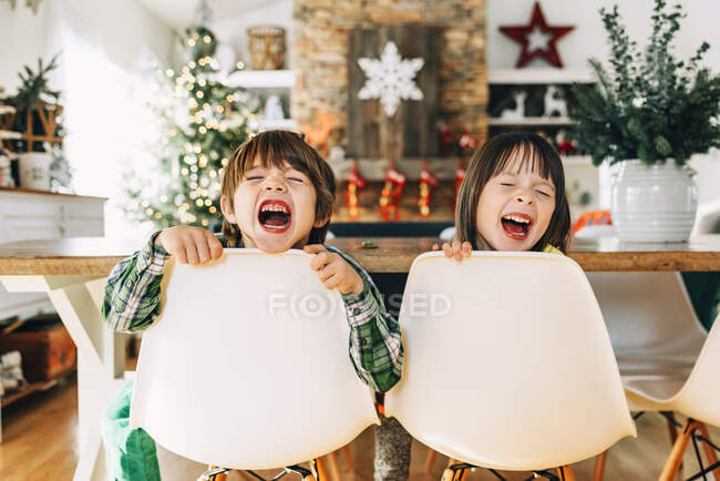 Garçon et fille assis à la table à manger déconner à Noël — Photo de stock