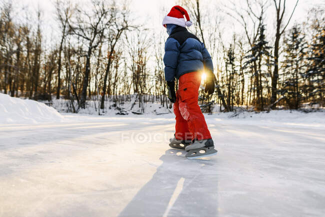 Boy wearing a santa hat ice-skating on a frozen lake — Stock Photo