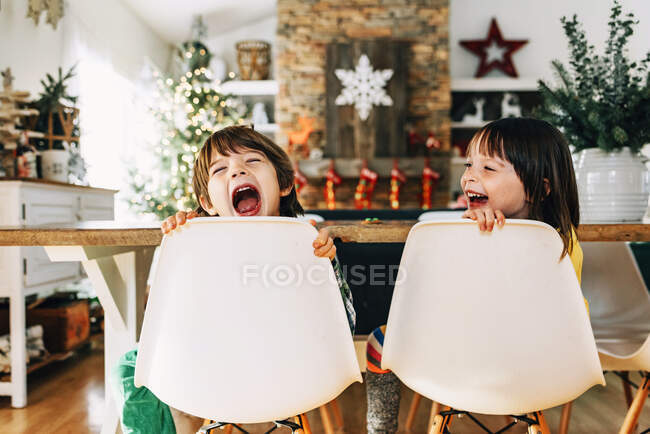 Garçon et fille assis à la table à manger déconner à Noël — Photo de stock