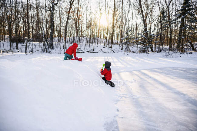 Two boys playing in the snow by a frozen lake — Stock Photo