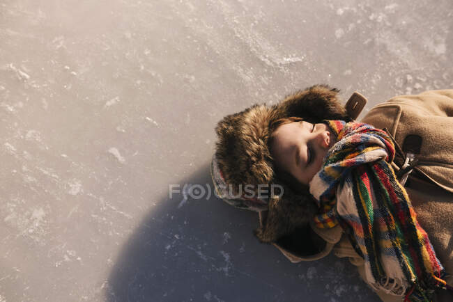 Мальчик лежит на замерзшем озере на природе — стоковое фото