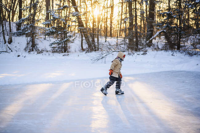 Мальчик катается на коньках по замерзшему озеру на природе — стоковое фото
