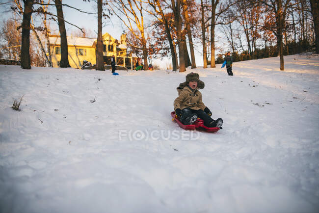 Boy sledging down a hill on nature — Stock Photo