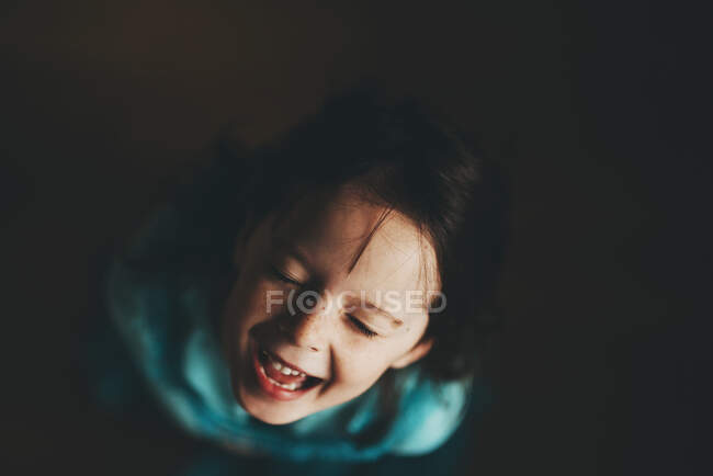 Sopra la testa di giovane ragazza ridendo su sfondo nero — Foto stock