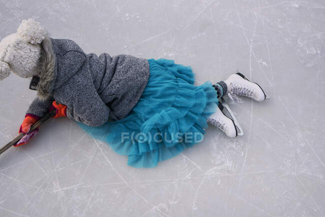 Дівчина лежить на замерзлому озері, тримаючи хокейну палицю — стокове фото