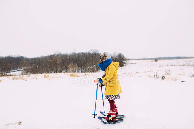 Дівчина катається на снігоступах у сільському зимовому пейзажі — стокове фото