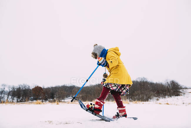 Дівчина катається на снігоступах у сільському пейзажі — стокове фото