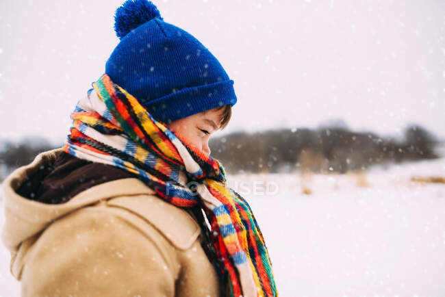 Ritratto di un ragazzo sulla neve avvolto in un cappello e una sciarpa — Foto stock