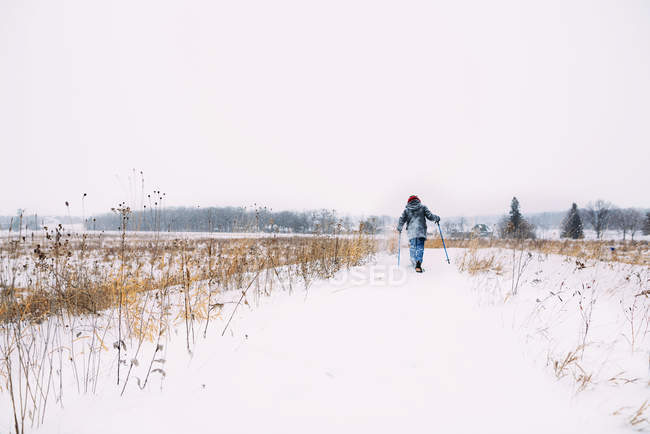 Ragazzo che cammina sulla neve con le ciaspole — Foto stock