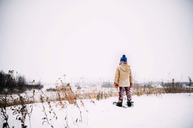 Menino andando na neve usando sapatos de neve — Fotografia de Stock