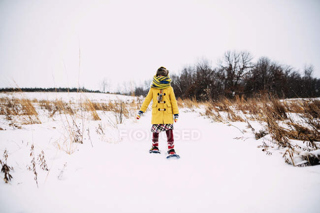 Menina de pé na neve usando sapatos de neve — Fotografia de Stock