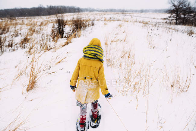 Chica caminando en la nieve usando raquetas de nieve - foto de stock