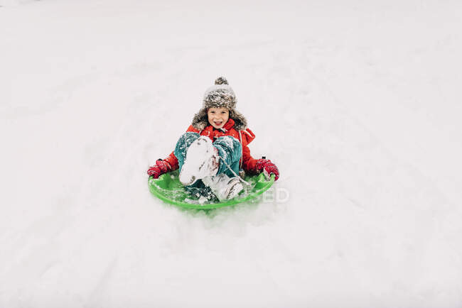 Молодая девушка катается на санках в снегу — стоковое фото