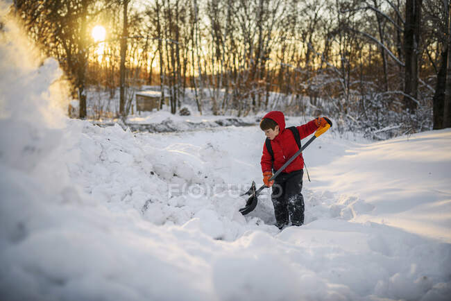 Хлопчик скидає сніг в саду — стокове фото