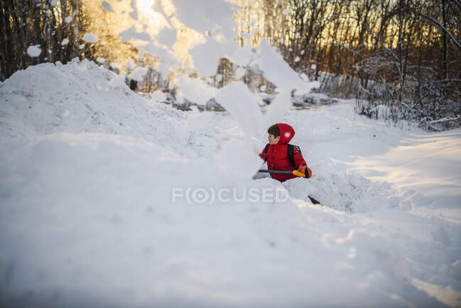 Хлопчик скидає сніг в саду — стокове фото