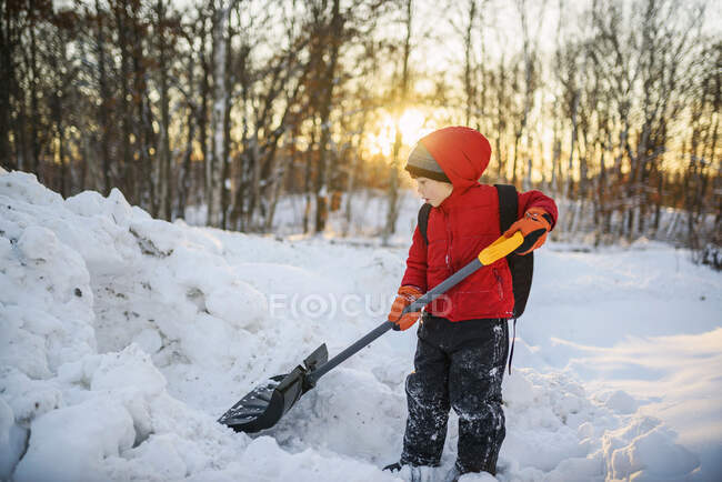 Chico paleando nieve en el jardín - foto de stock