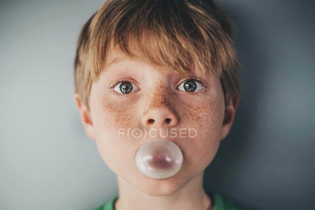Retrato de um menino com sardas soprando uma bolha de chiclete — Fotografia de Stock