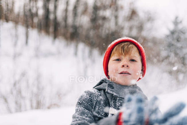 Хлопчик стоїть на відкритому повітрі кидає сніг — стокове фото